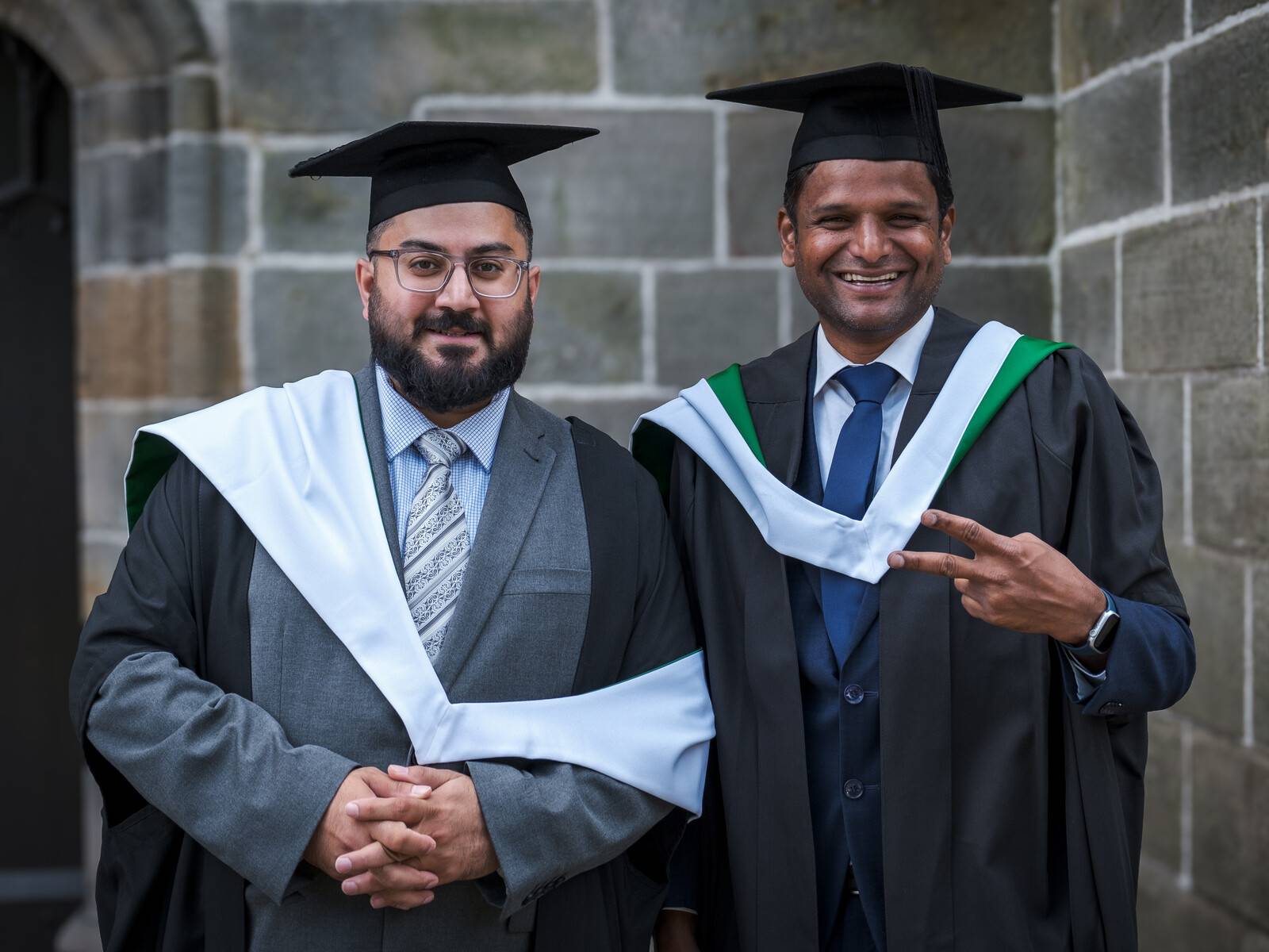 Online students Asad and Manikandan smile together in their graduation robes outside King's College