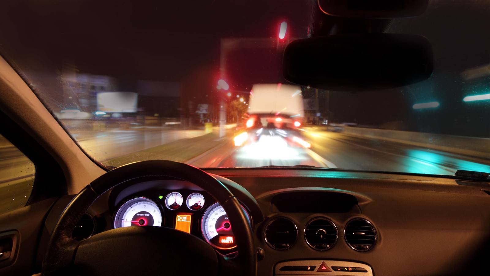 Car dashboard at night as seen from the driver's seat.