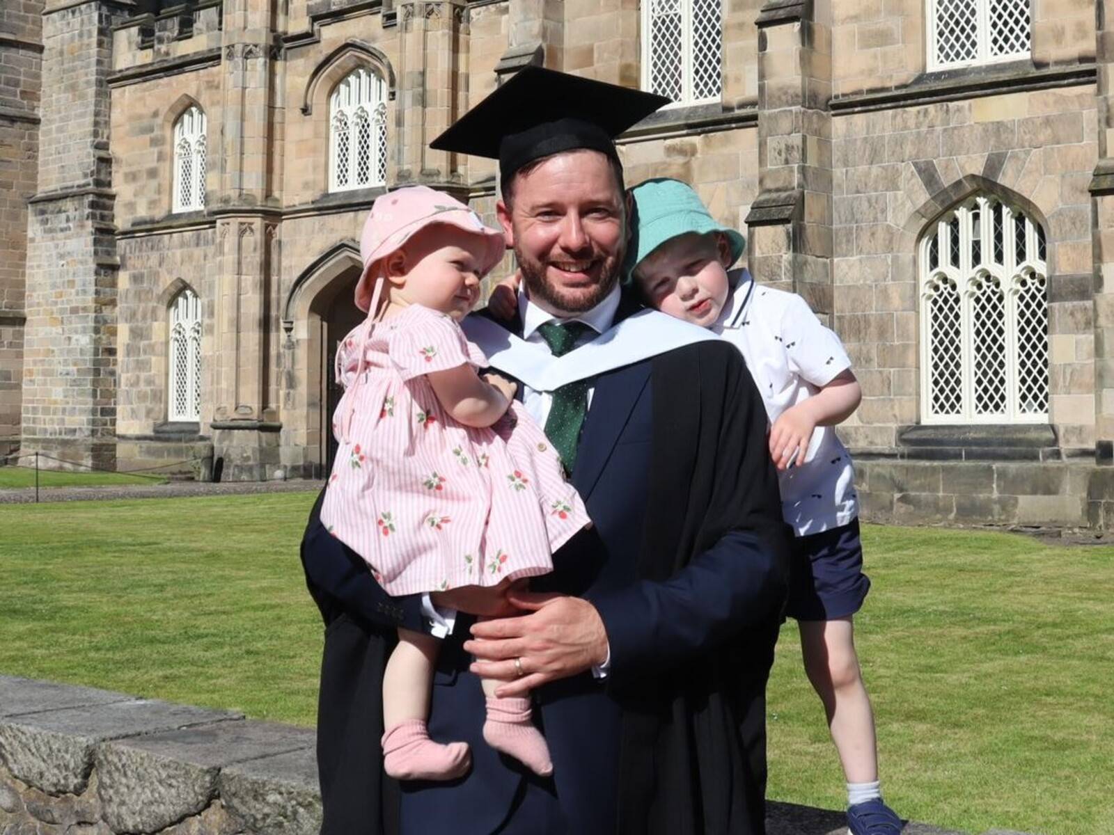 David Wilson smiles in the sunshine with his children at his graduation outside King's College